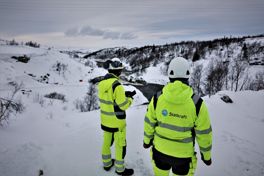 Two collegues standing on top of a snowy mountain